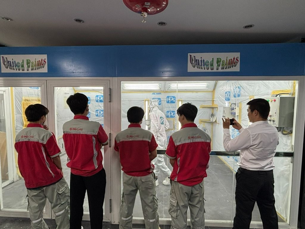 Kỹ thuật viên MG đứng ngoài cửa kính quan sát buồng sơn
